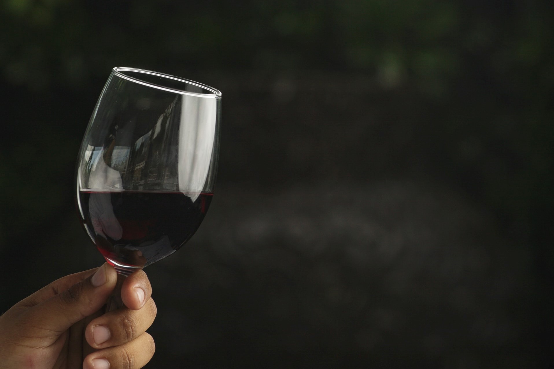 hand holding a glass of red wine with dark background
