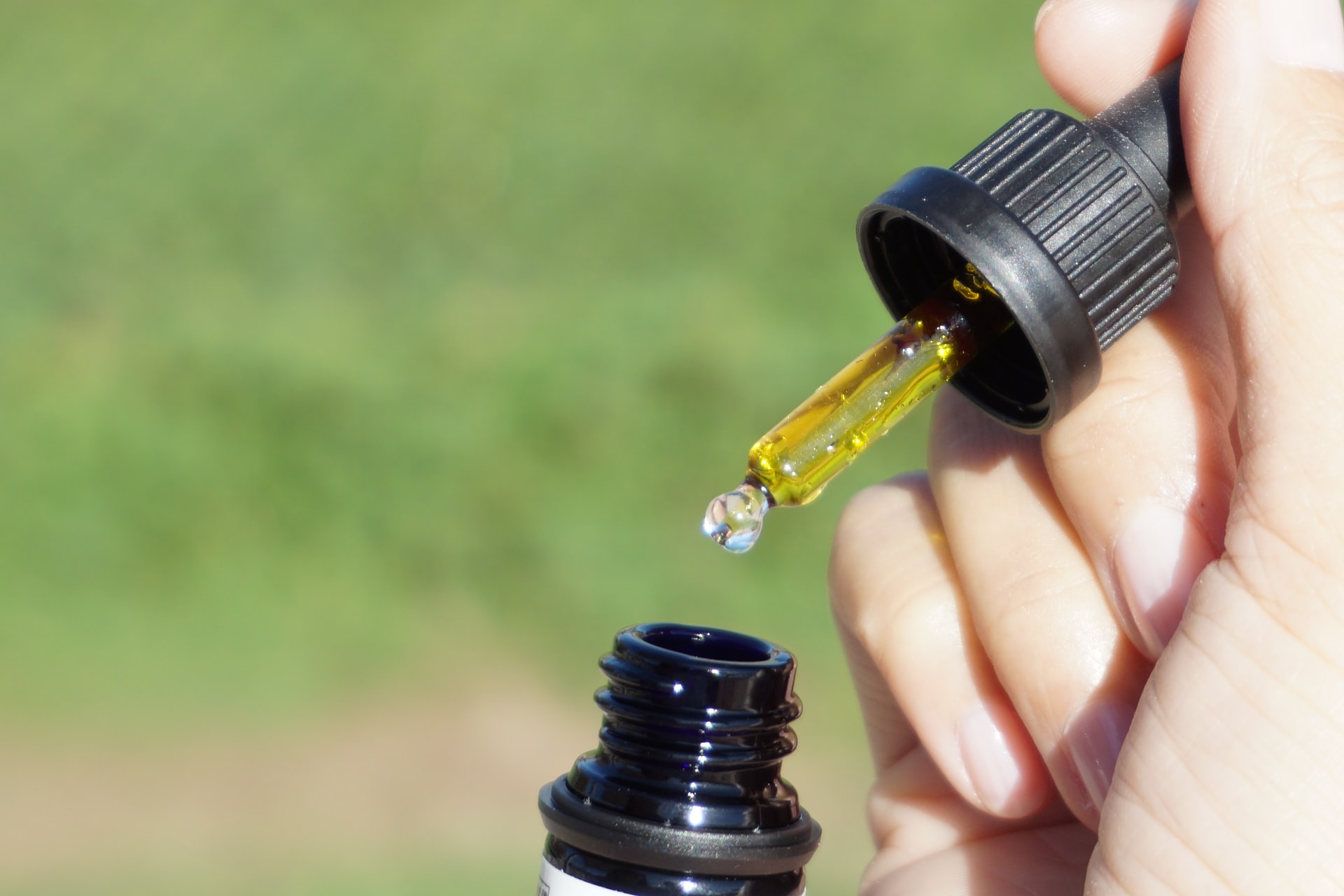 hand using oil dropper into small bottle