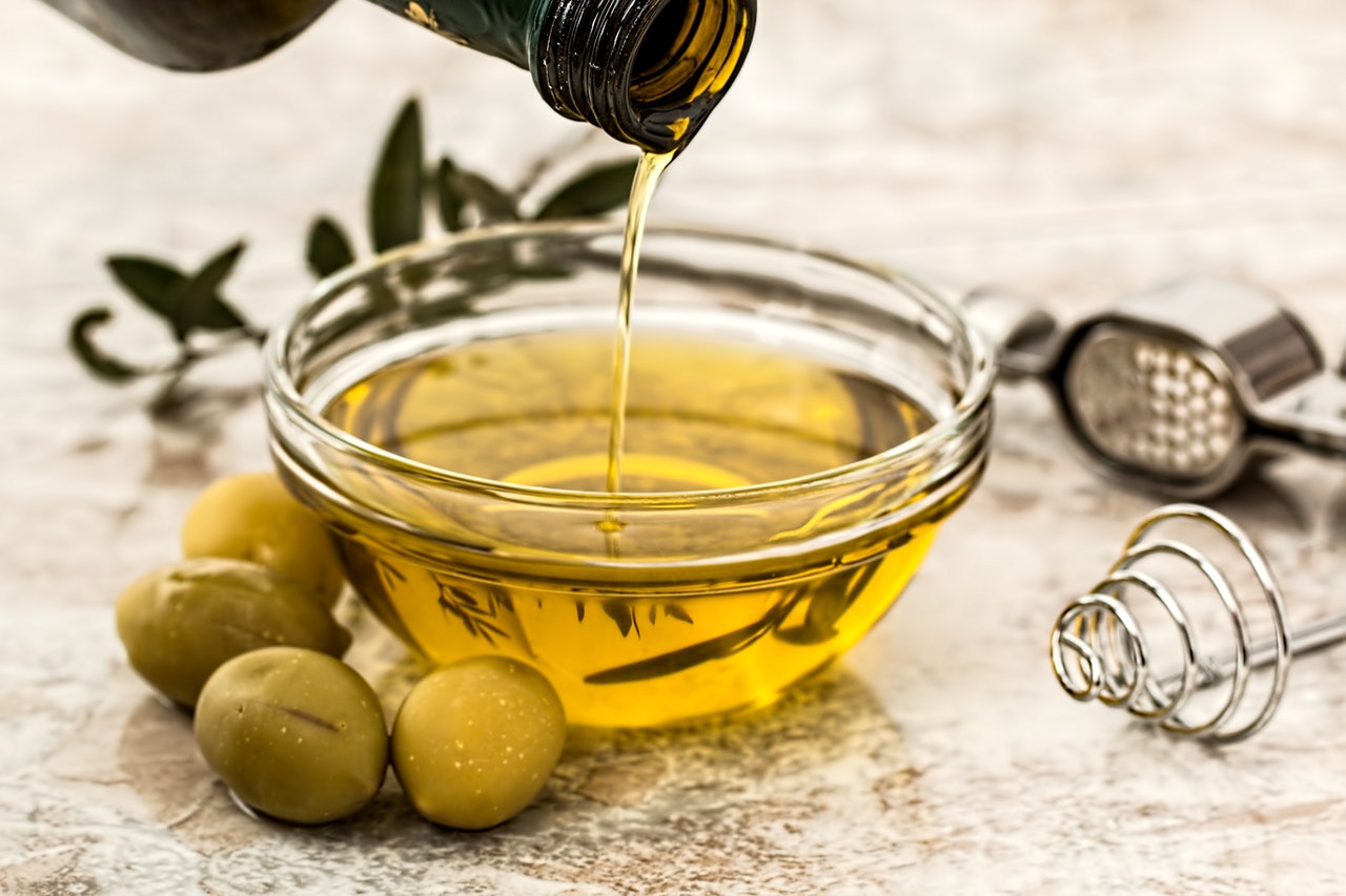 olive oil being poured into small glass bowl